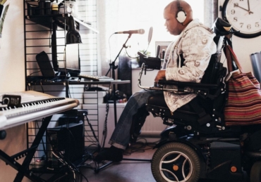 Side view of disabled musician with headphones in recording studio
